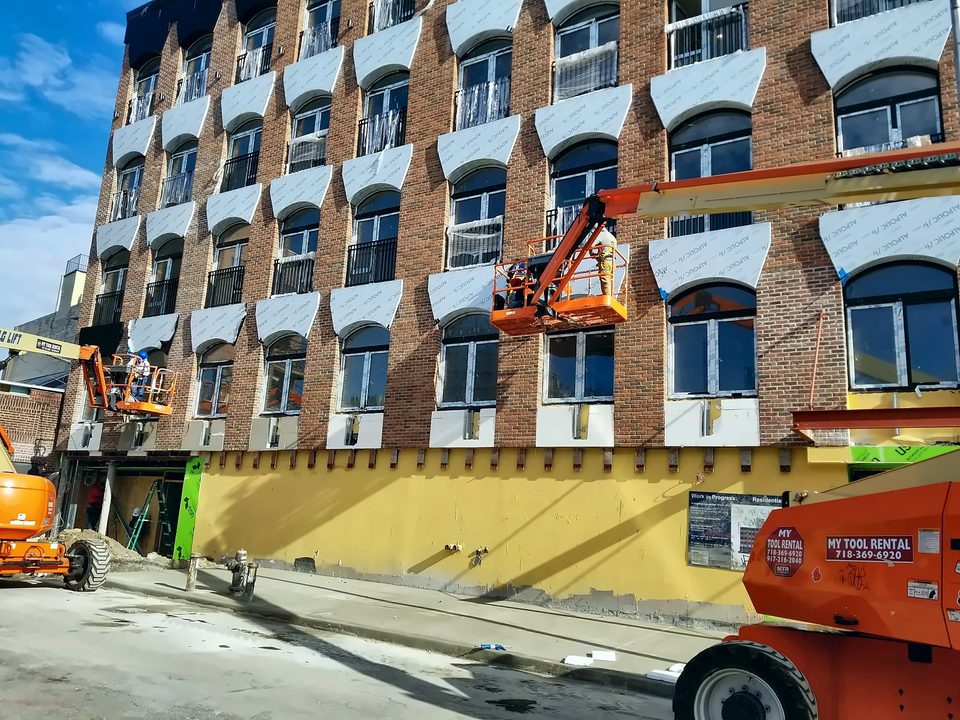 Boom lifts at a brick facade with decorative window trim