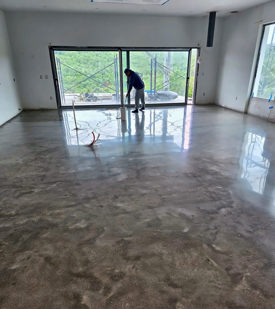 Crew hand-working a metallic epoxy floor beside a glass wall