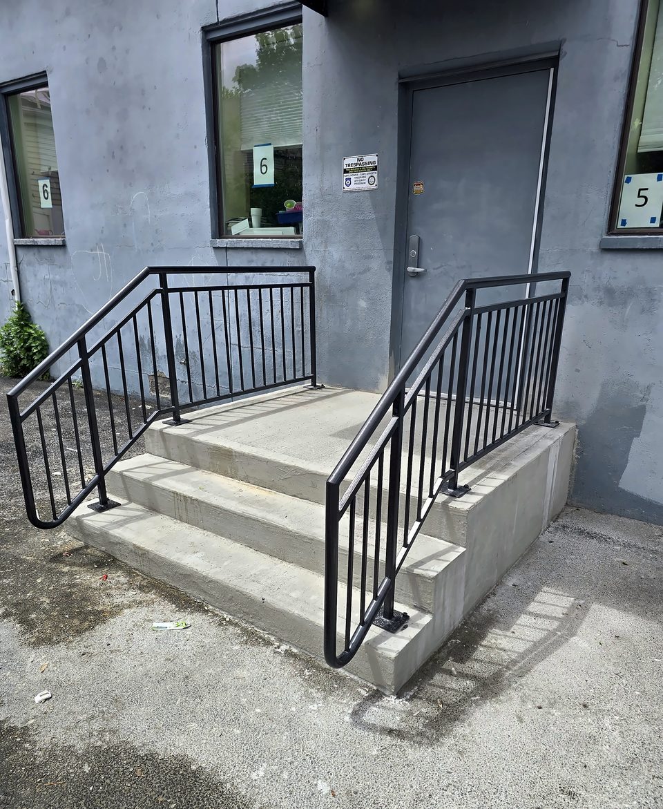After: new stairs with code-compliant pipe handrails, May 2026