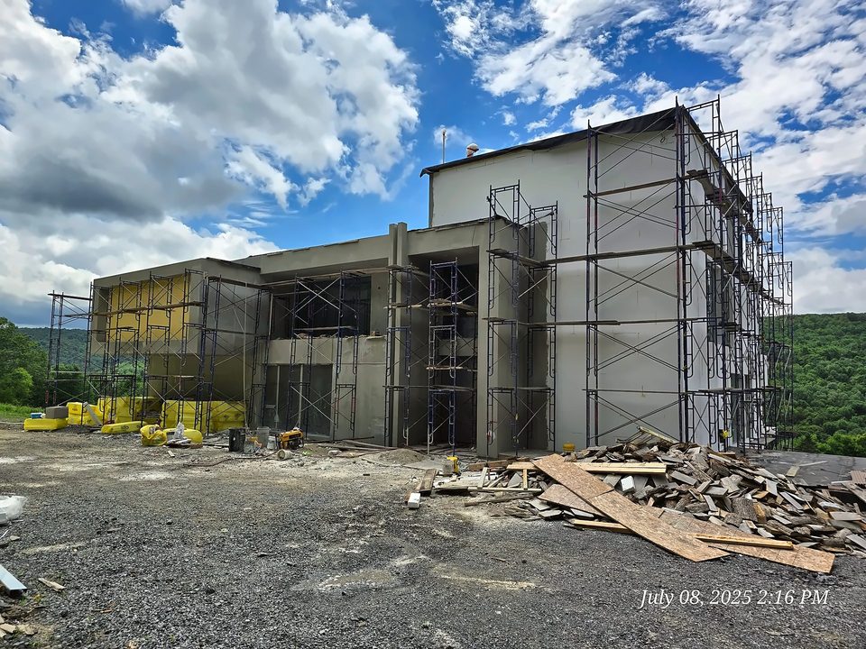 EIFS in progress on a new home with a scaffold tower under a blue sky