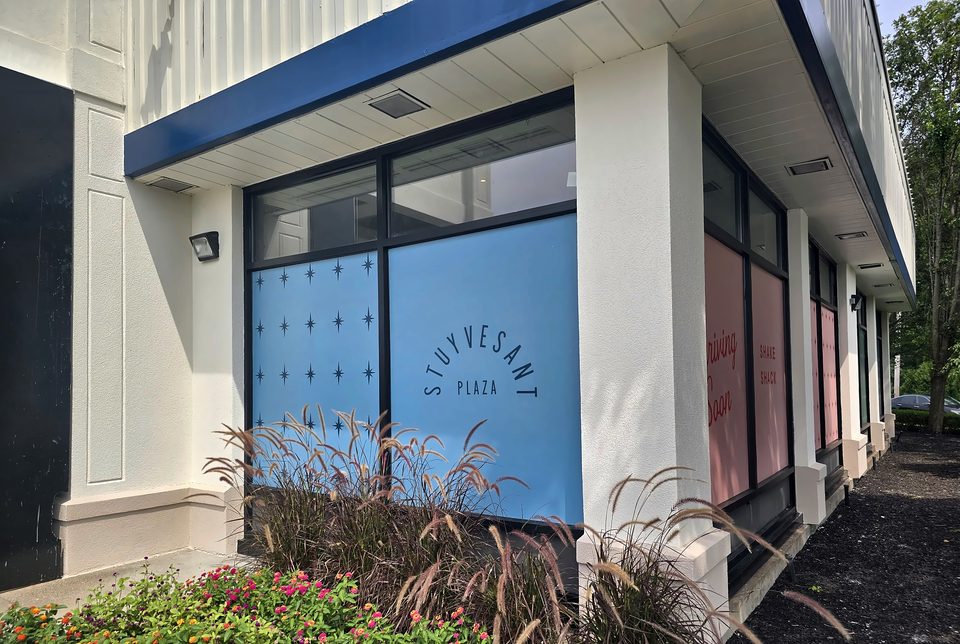 The storefront columns and band before the stucco repair and decorative finish, August 2026
