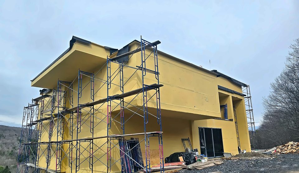 Summer 2025: basecoat stage under full-perimeter scaffold