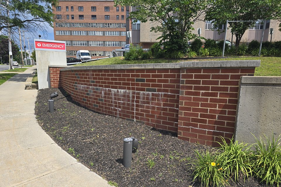 Before — efflorescence streaking the retaining wall at the emergency entrance