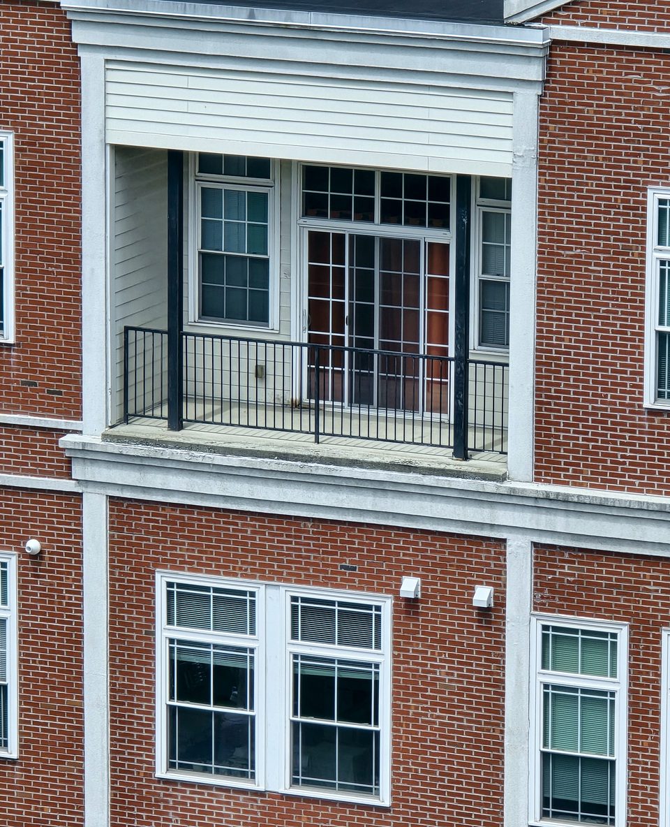 The balcony and EIFS band before the work, June 2026