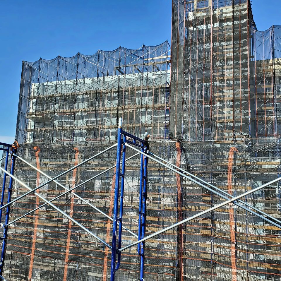 Pipe scaffold with debris netting — full facade enclosure