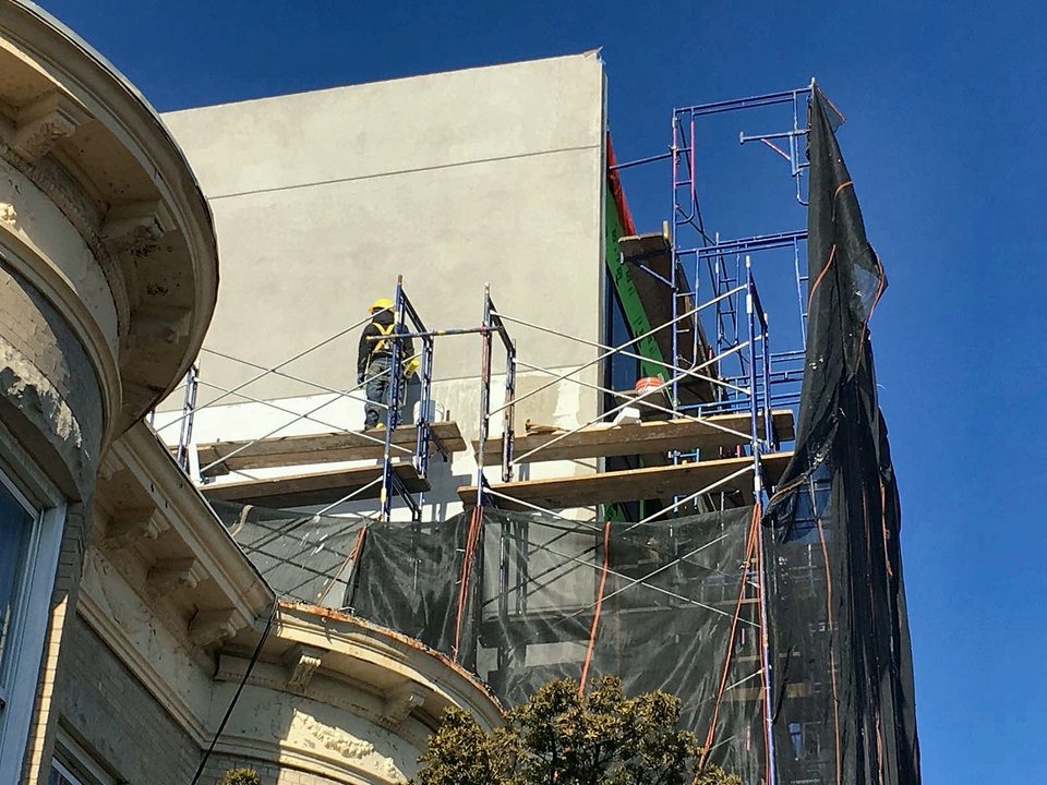 Crew restoring a historic facade cornice from scaffold, 2019