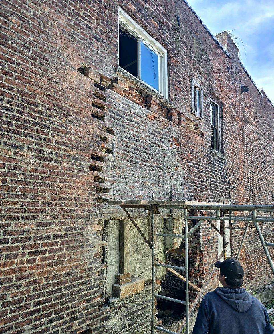 During: brick toothed in course by course from pipe scaffold, May 2026