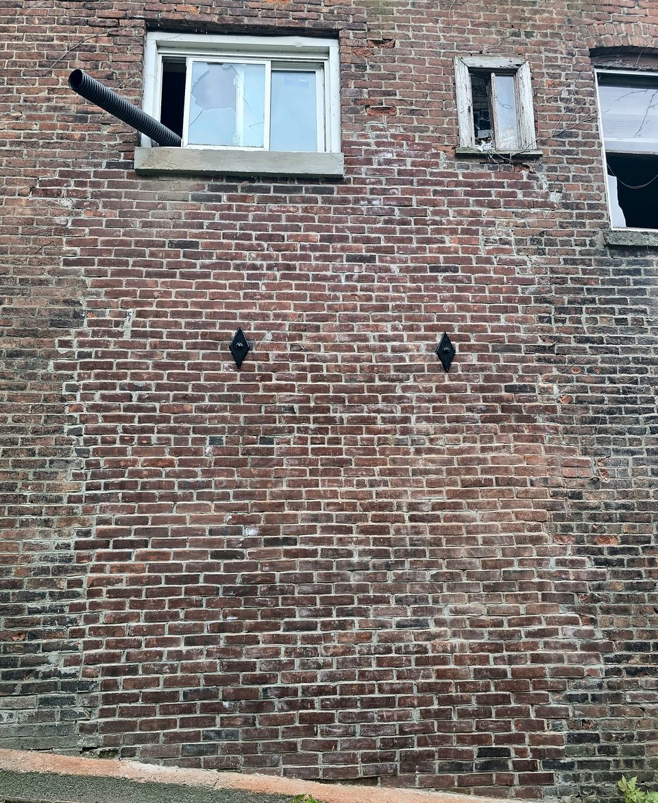 After: helical-tie anchor plates in the rebuilt wall, August 2026