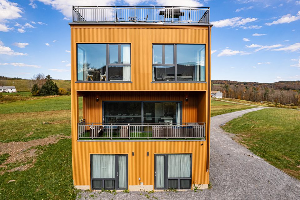 Front elevation: metal panels, wood-look composite siding and stacked balconies